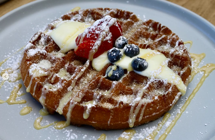 Churro waffle breakfast in Las Vegas topped with fresh berries, cream cheese frosting, and dulce de leche drizzle at Early Birds.